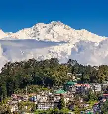 Darjeeling hill town houses on a forested slope with the snow-capped Kangchenjunga range behind
