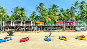Colorful beach shacks with kayaks on Goa beach and palm trees