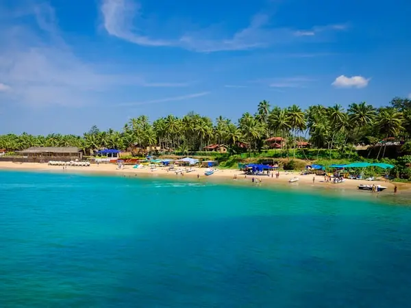 Turquoise ocean water and sandy beach with palm trees and beach shacks