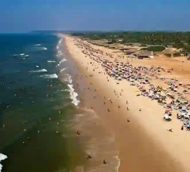 Aerial view of crowded Goa beach with tourists and colorful umbrellas
