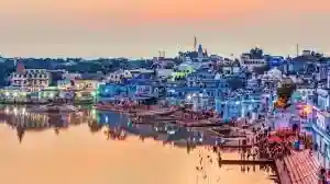 Pushkar town with lakeside ghats and blue houses lit up at dusk in Rajasthan
