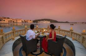 Couple at a candlelit dinner on a terrace overlooking Lake Pichola at sunset in Udaipur